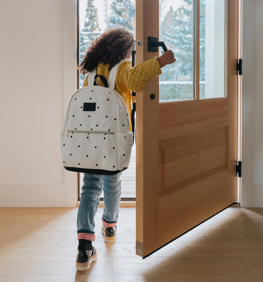 a girl of color walking out door to school